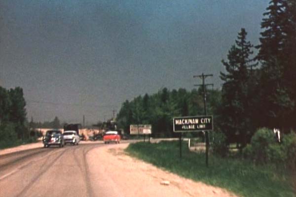 US-31 northbound (present-day M-108/Nicolet Ave) at the southern Mackinaw City village limit as it veers easterly toward the State Ferry Docks via present-day Old 31. Nicolet Avenue to the north has been closed and the roadway is being raised to meet the realigned US-23/US-27 route at the new, higher grade level. (1956)